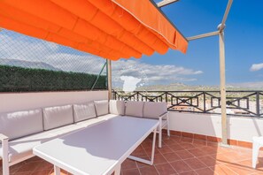 A terrace with a white table and sofa, an orange awning, and a view of the city. - CostaBlancaDreams - Calpe Bay, Sonrisa in Calpe (Calpe / Calp)