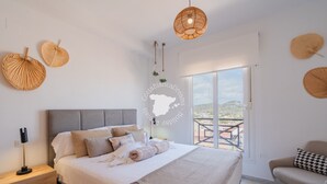 Quarto com cama, mesa de cabeceira e vista para o exterior.