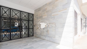 Um interior moderno com porta de vidro, parede de pedra e chão revestido de azulejos.