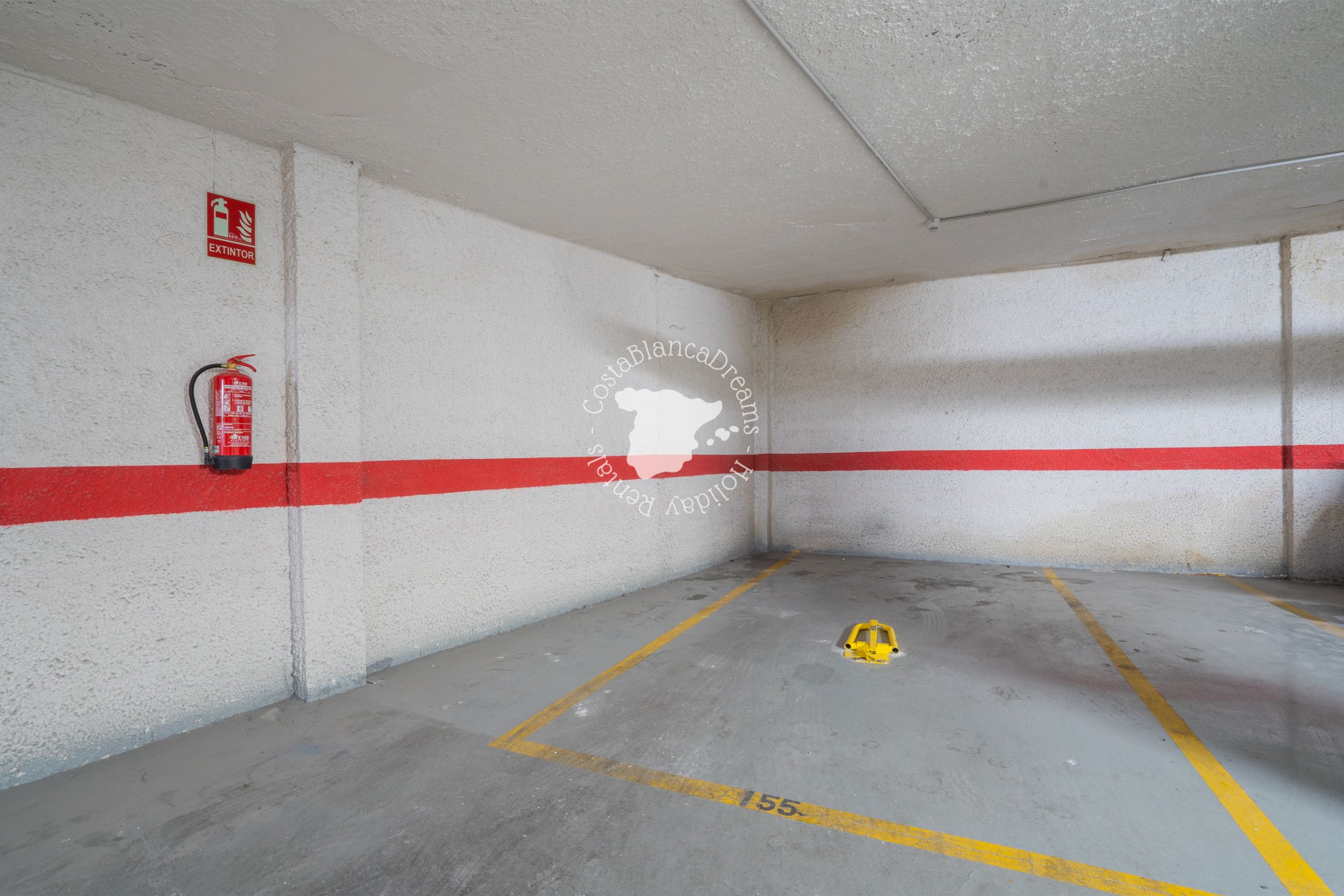 A parking garage with white walls, red and white stripes, and a fire extinguisher mounted on the wall.