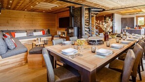 A modern interior with a long dining table set for a meal, a sofa, and a fireplace.