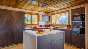 A modern kitchen with a central island, dark cabinetry, and a view of the outdoors.