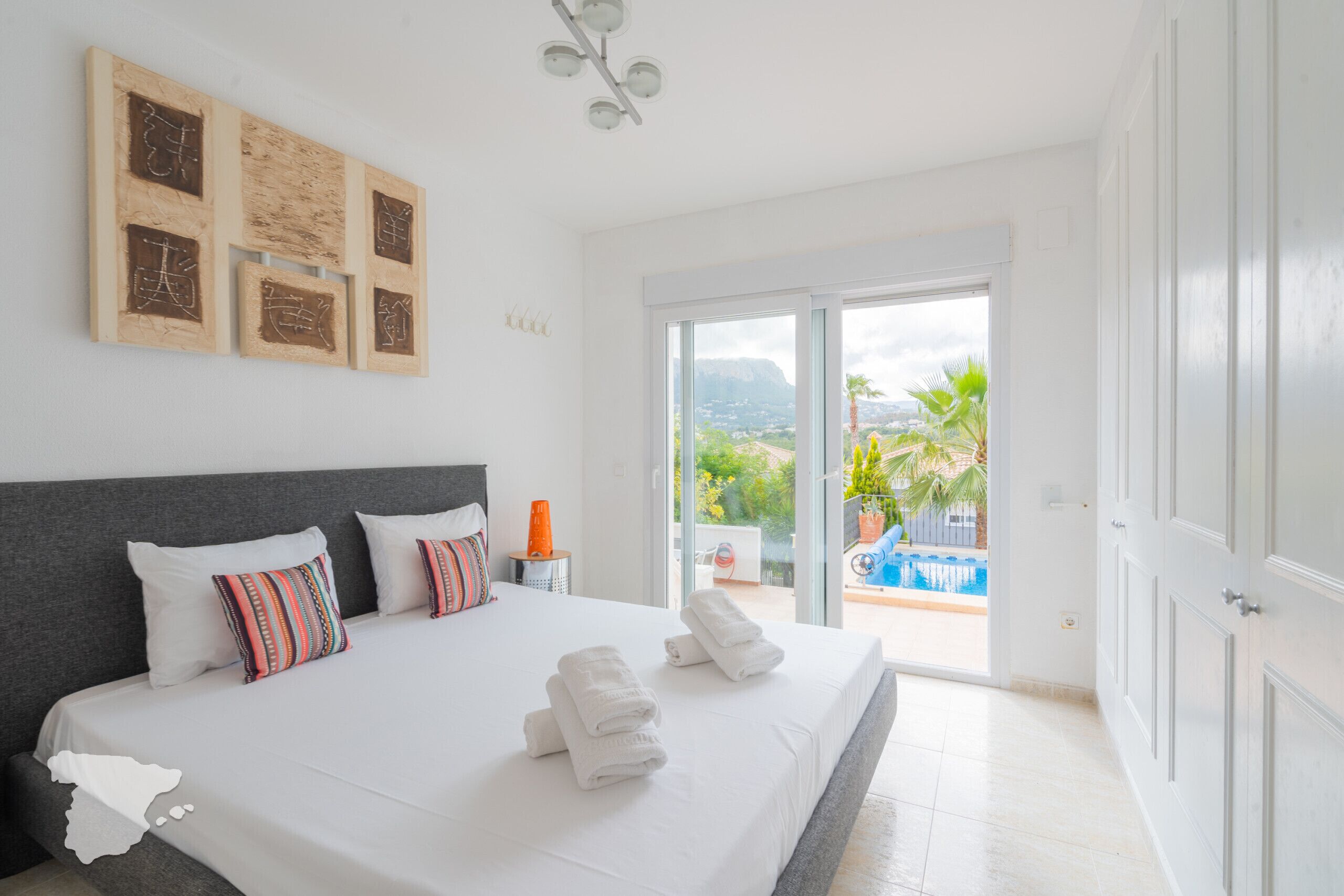 Un dormitorio con una cama grande, una mesita de noche y vista a una piscina.