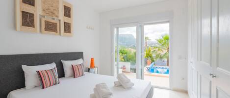 Un dormitorio con una cama grande, una mesita de noche y vista a una piscina.