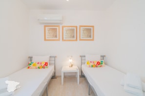 A room with two beds, a small table with a lamp, and three heart-shaped wall decorations.