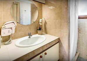 Un baño con lavamanos, espejo y toallero.