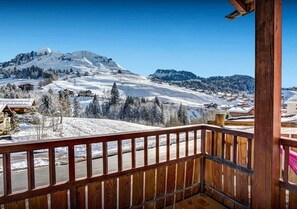 Un balcón de madera con vistas a un paisaje montañoso cubierto de nieve.