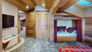 A cozy bedroom with a bed, a television, and a wooden ceiling. - Ski base piste views, 14 people, pool and sauna (Le Grand-Bornand)