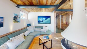 A modern living room with a curved sectional sofa, a small wooden coffee table, and a large painting on the wall. - Ski base piste views, 14 people, pool and sauna (Le Grand-Bornand)
