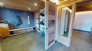 A room with a wooden bench, a wall-mounted coat rack, and a wooden door with a mirror. - Ski base piste views, 14 people, pool and sauna (Le Grand-Bornand)