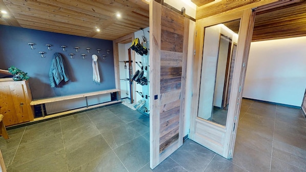 A room with a wooden bench, a wall-mounted coat rack, and a wooden door with a mirror.