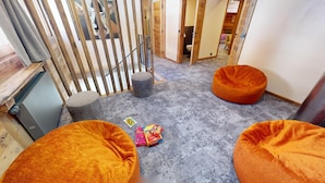 A room with two orange bean bags, a small table with toys, and a grey carpet. - Ski base piste views, 14 people, pool and sauna (Le Grand-Bornand)