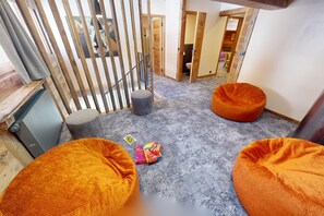 A room with two orange bean bags, a small table with toys, and a grey carpet. - Ski base piste views, 14 people, pool and sauna (Le Grand-Bornand)