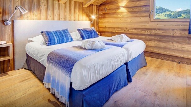 A wooden-paneled room with a bed, a nightstand, and a window with a view of the outdoors. - Luxury chalet with swimming pool and jacuzzi (Manigod)