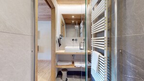A modern bathroom with a glass shower enclosure, a white bathtub, and a towel rack. - Magnificent T4 in a renovated traditional chalet (Le Grand-Bornand)