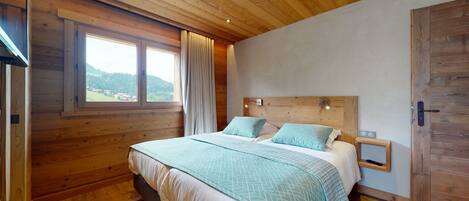 Un dormitorio con paneles de madera, una cama, una mesita de noche y una ventana con vistas al exterior.