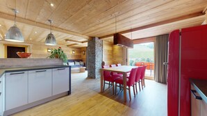 Una cucina moderna con zona pranzo, soffitto in legno e vista sull'esterno.