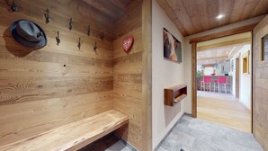 Un interno in legno con una panca, ganci a parete, una decorazione a forma di cuore e una piccola mensola.
