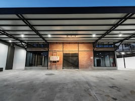 Un edificio espacioso de estilo industrial con fachada de ladrillo, ventanas amplias y suelo de hormigón.