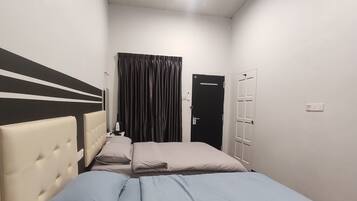 Een slaapkamer met een bed, plafondventilator, een deur en een raam met gordijnen.