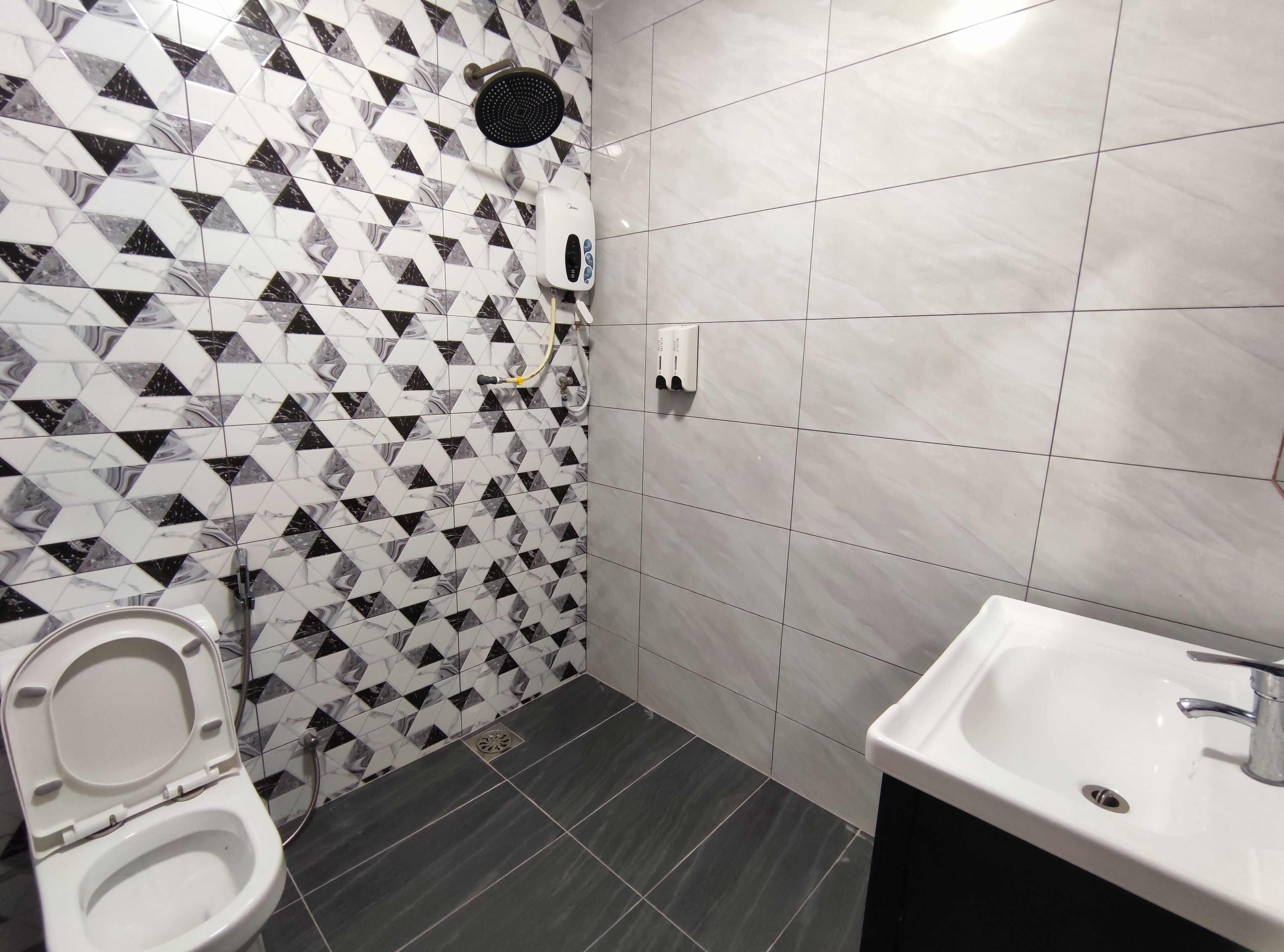 Et badev ærelse med toilet, håndvask, bruser og hårtørrer.