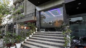 Entrada de hotel con diseño moderno, destacando una fachada de vidrio y una escalera que conduce a la recepción.