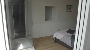 A bedroom with a glass shower enclosure, a single bed, and a small window. - Longère Bretonne sur Bord de Rivière (Arzano)