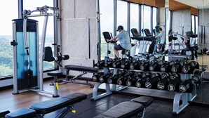 A gym with various exercise equipment, including treadmills and dumbbells, and large windows offering a view of the outdoors. - Modern room overlooking the city center Chiang Mai (Chang Wat Chiang Mai)