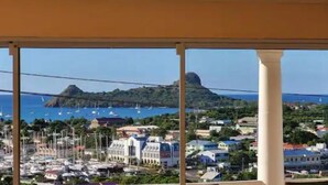 A coastal town with a marina, buildings, and a prominent hill in the background. - Marina View Villa (Gros Islet)