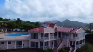 A multi-story building with a swimming pool, balconies, and a mountainous backdrop. - Marina View Villa (Gros Islet)