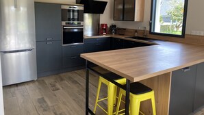 Cucina moderna con frigorifero in acciaio inossidabile, forno integrato e un'ampia finestra che garantisce luce naturale.