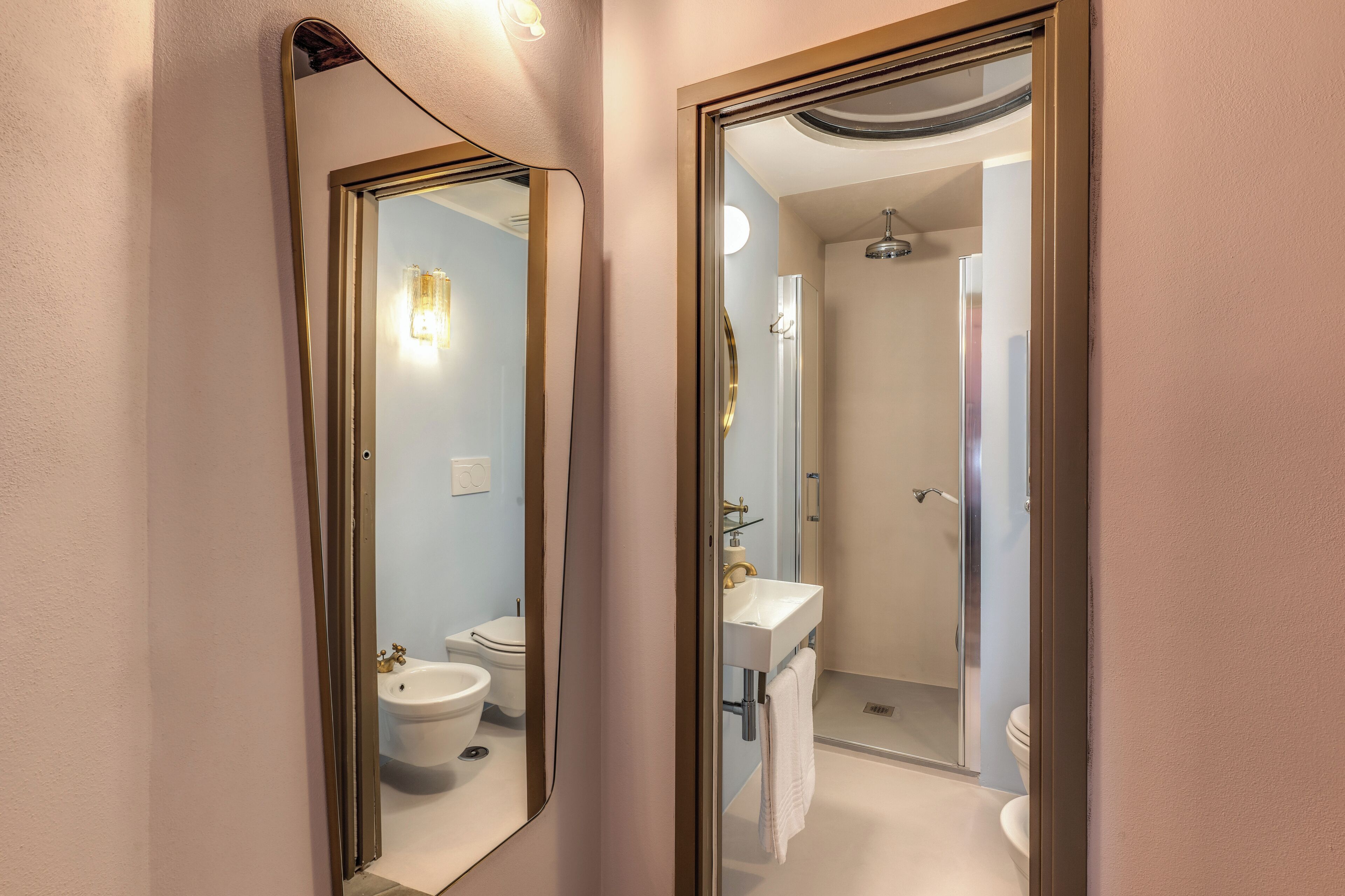 A bathroom with a toilet, bidet, sink, and shower.