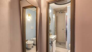 A bathroom with a toilet, bidet, sink, and shower.