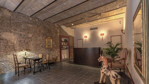 Un hall d’entrée avec un mur en briques, un comptoir d’accueil, une sculpture équestre et un espace détente avec des chaises et une table.
