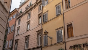 Un immeuble à plusieurs étages, de style architectural classique, caractérisé par des fenêtres en arc et des volets.