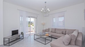 Een moderne woonkamer met een bank, een salontafel, een tv op een meubel en een balkon met uitzicht.