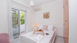 Een slaapkamer met een bed, een nachtkastje met een lamp, een raam met uitzicht en een schuifdeur naar een balkon.