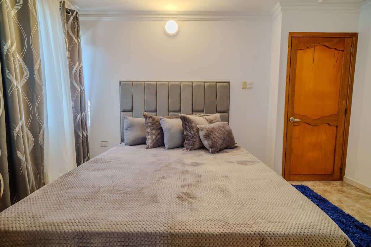 A bedroom with a large bed, a headboard, and a wooden door.