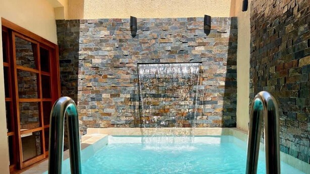 An indoor swimming pool with stone walls and metal railings.