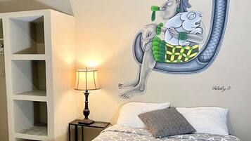Un dormitorio con cama, lámpara, un mural en la pared y una estantería.