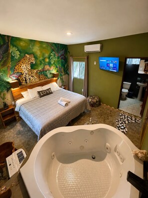 Un dormitorio con una cama grande, un mural de un leopardo, un televisor y un baño con bañera.