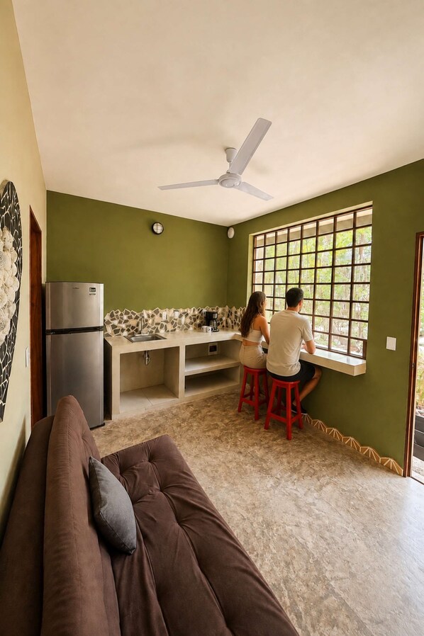Un espacio habitable compacto con kitchenette, un sofá y una ventana con vistas.