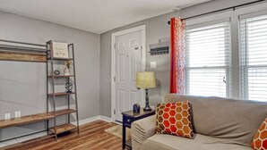 A living room with a sofa, a lamp, a shelf with decorative items, and a door. - The Cozy Cottage of Florence!

 (Florence)