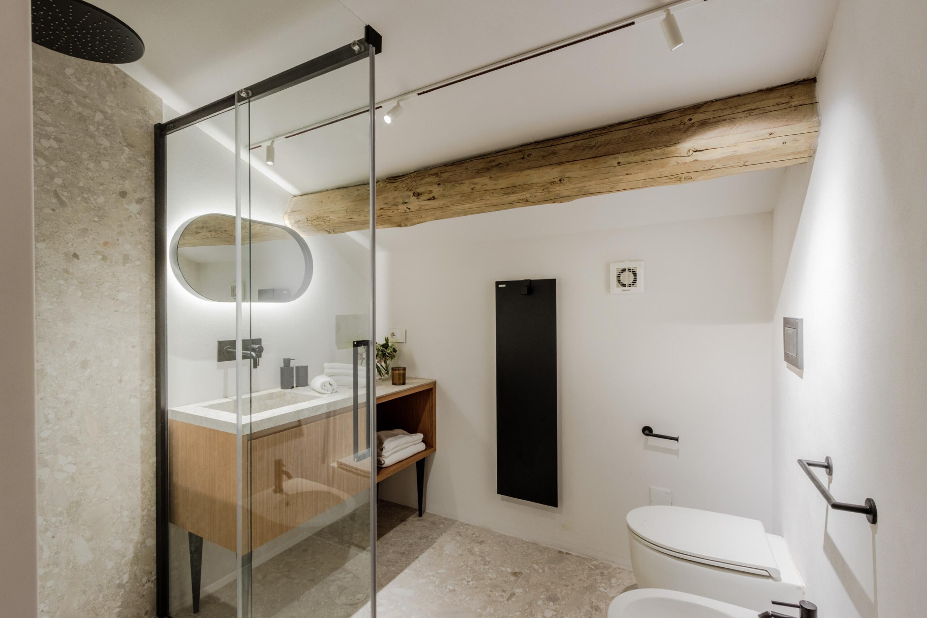 Ein modernes Badezimmer mit Glasdusche, Holzwaschtisch und minimalistischem Design.
