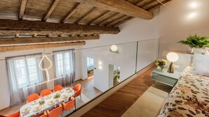 A modern interior with a dining area, a bed with floral bedding, and a wooden ceiling. - The Victory Penthouse (Lucca)