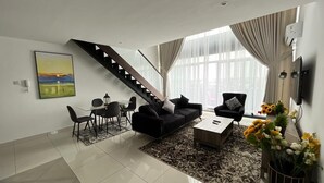 Ein modernes Wohnzimmer mit Treppe, Essbereich und einem großen Fenster mit Vorhängen.