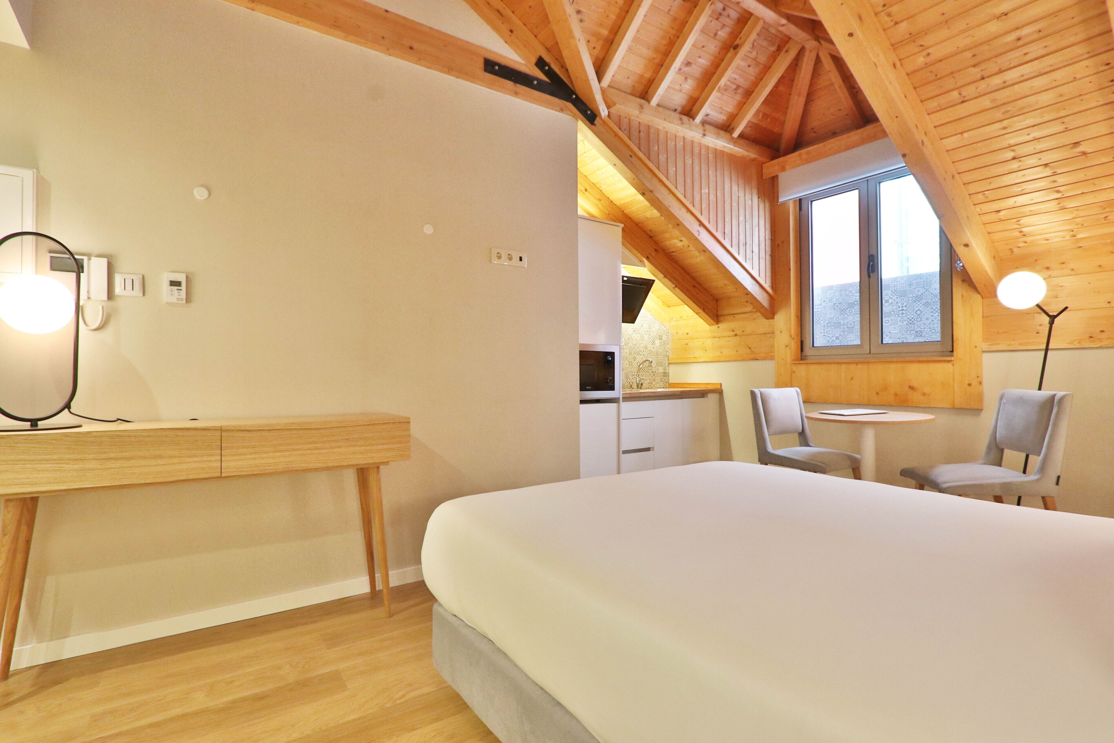 A bedroom with a wooden ceiling, a bed, a desk, and a chair.