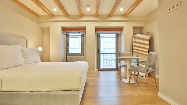 A bedroom with a large bed, a small table with chairs, and a balcony with a railing. - BOULEVARD Boutique Studios   (Lisbon)