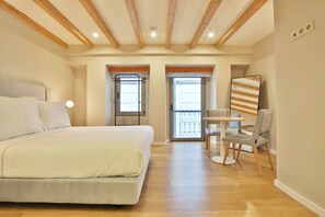 A bedroom with a large bed, a small table with chairs, and a balcony with a railing. - BOULEVARD Boutique Studios   (Lisbon)