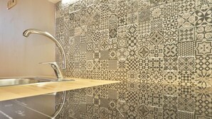 A kitchen with a stainless steel sink, a wooden countertop, and a backsplash with patterned tiles. - BOULEVARD Boutique Studios   (Lisbon)